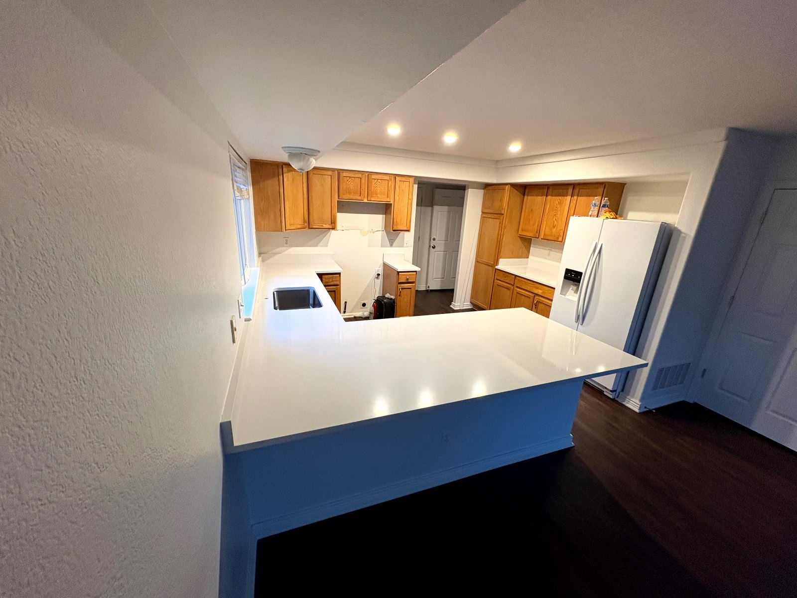 Open-Concept Bar Top — Extended overhang bar top with a polished white finish